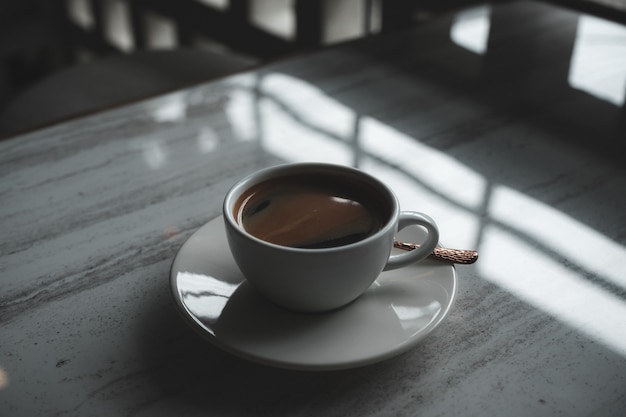 Closeup imagen de una taza blanca de café caliente en la mesa