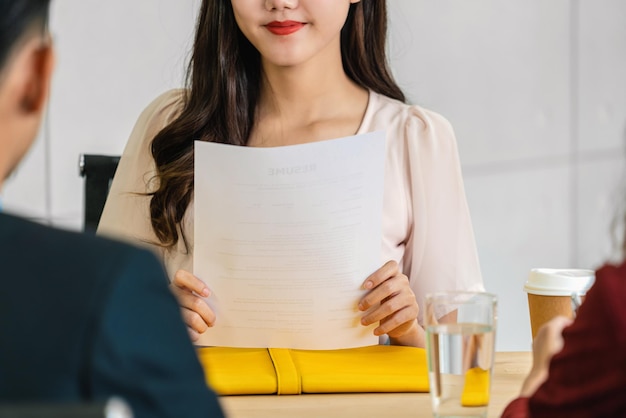 Closeup jovem asiática formada segurando o documento de currículo e se preparando para o gerente