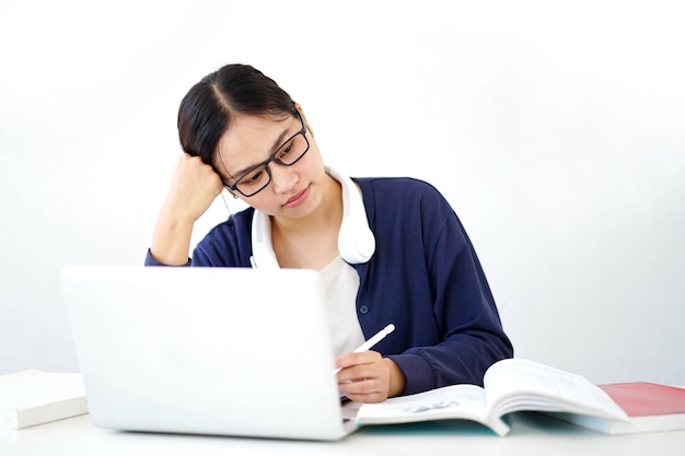 Closeup jovem estudante asiática em pano casual mostra tédio em fazer relatórios com laptop