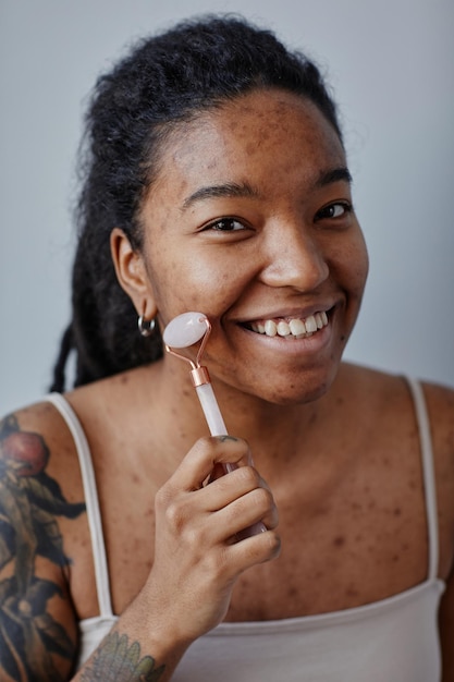 Foto closeup jovem negra usando massageador facial e sorrindo mínimo