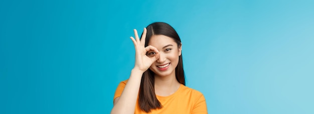 Closeup, linda e sonhadora mulher asiática, tenra e escura, corte de cabelo curto, ok, sinal de ok, olhe através do círculo smil