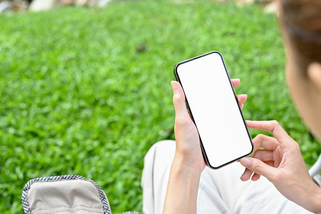 Closeup linda jovem asiática usando um smartphone no parque verde