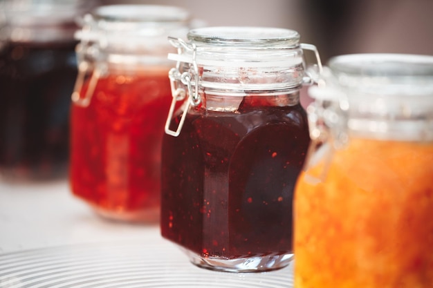 Closeup linha de vários vidros com geléia de frascos de laranja amarelo vermelho conserva confiture pozzy na mesa conceito de café da manhã fundo de cozinha conceito de alimentação saudável conceito de conservação