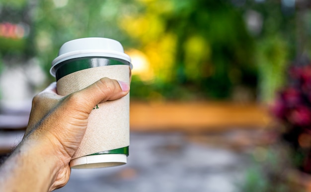 Closeup mano masculina sosteniendo una taza de café caliente con enfoque suave