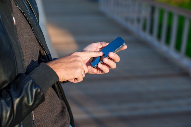 Closeup manos del hombre mediante teléfono móvil al aire libre