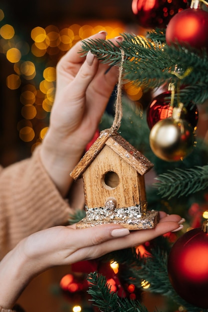 Closeup manos de mujer irreconocible sosteniendo juguete de Navidad en el fondo del árbol de Navidad