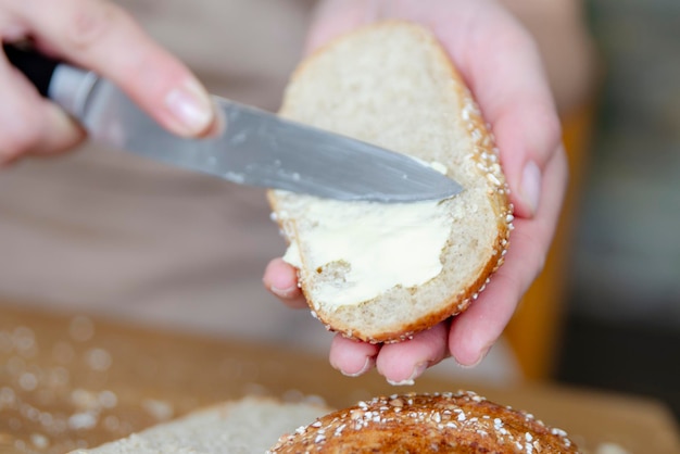 Closeup de las manos de las mujeres extendiendo mantequilla en una rebanada de pan comida rápida para hacer senderismo o si no