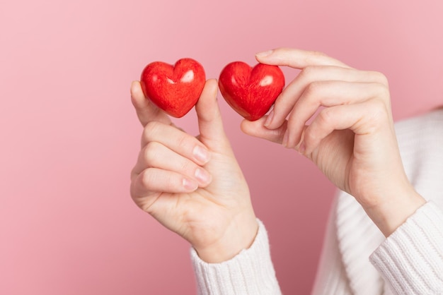 Closeup manos sosteniendo corazón sobre fondo rosa concepto de día de san valentín