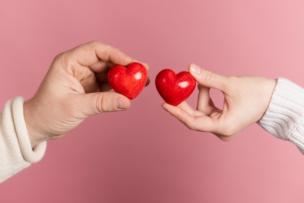 Closeup manos sosteniendo corazón sobre fondo rosa concepto de día de san valentín