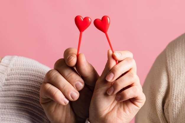 Closeup manos sosteniendo corazón sobre fondo rosa concepto de día de san valentín