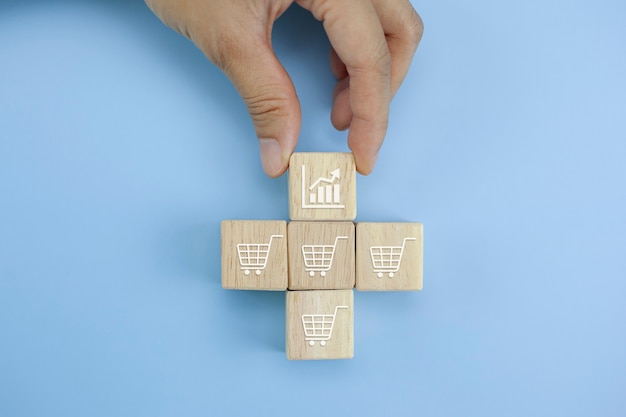 Foto closeup manos voltea cubo con símbolo de carrito de compras de icono