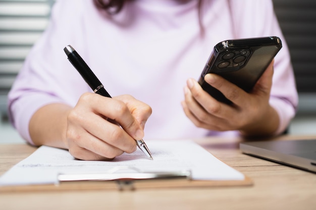 Closeup mão de empresária escrevendo documentos de assinatura em papel na mesa de escritório