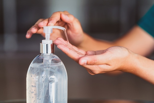 Closeup mão de mulher asiática usando dispensador de bomba de gel desinfetante para lavagem de mãos antes do trabalho