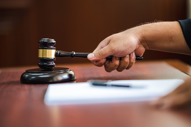 closeup mão Juiz com martelo na mesa de madeira dentro do tribunal