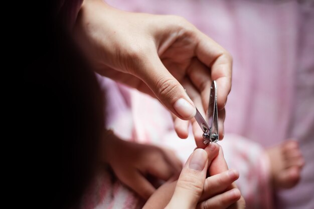 Closeup mão uma mãe corta as unhas de um bebê A mãe usa um cortador de unhas corta as unhas do bebê lentamente enquanto o bebê dorme para cortar facilmente