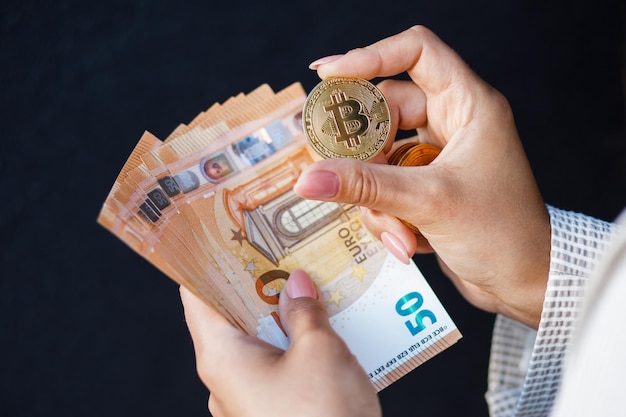 Closeup mãos da mulher segurando moedas de ouro de moeda criptográfica e notas de euro vestindo jaqueta branca O conceito de economia e salários de pagamentos em dinheiro