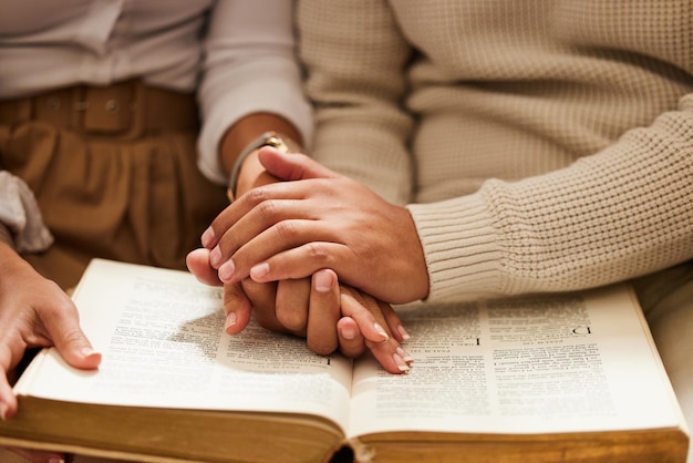 Closeup mãos e casal com a Bíblia orando e apoiando com amor prática espiritual e religiosa Zoom mão e homem com mulher oração e escritura pela fé, confiança e bem-estar com ligação