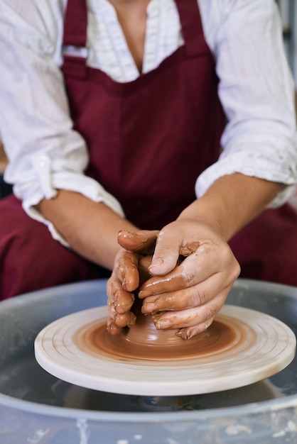Foto closeup mãos femininas torcendo argila em uma roda de oleiro