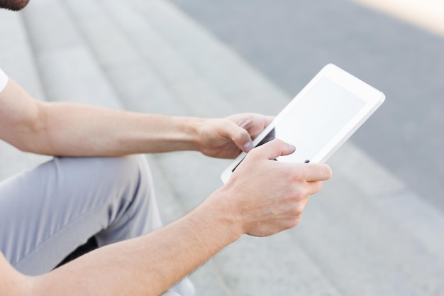 Closeup mãos masculinas segurando tablet digital enquanto está sentado em escadas de pedra, colheita, espaço de cópia. Conceito de negócios, pessoas e tecnologia