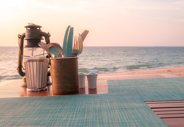 Closeup de la mesa de la cena establecida para una comida romántica en la playa con linternas en la mesa de madera