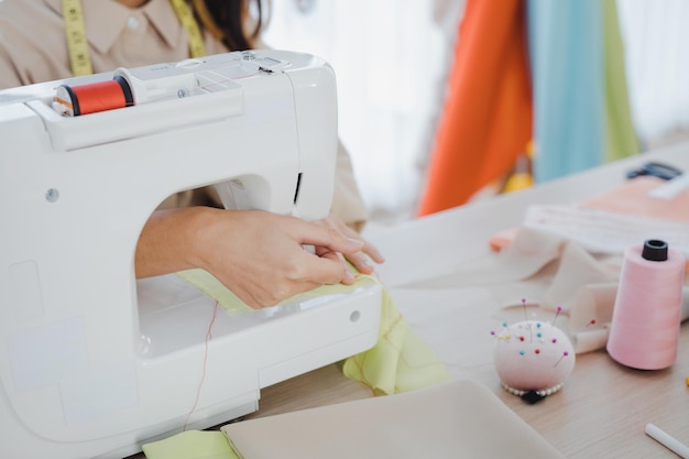 Closeup Modedesigner schneiden neue Kleidung mit Nähmaschinen im Studio. Designer mit Nähmaschine bei der Arbeit. Startup-Designer-Konzept.