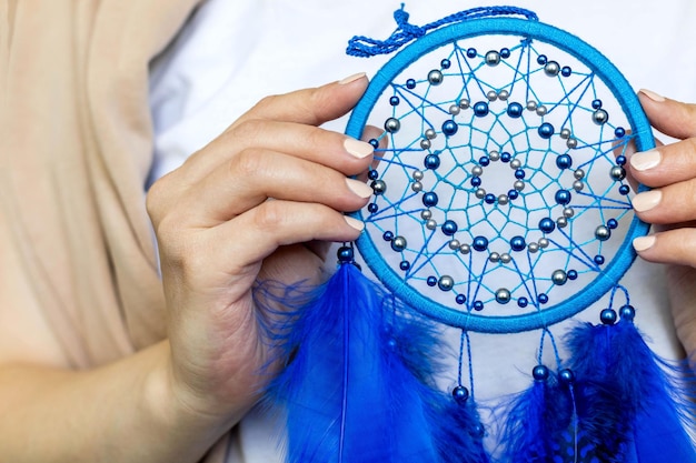 Closeup mujer artística posando sosteniendo atrapasueños con ilustraciones de plumas azules brillantes