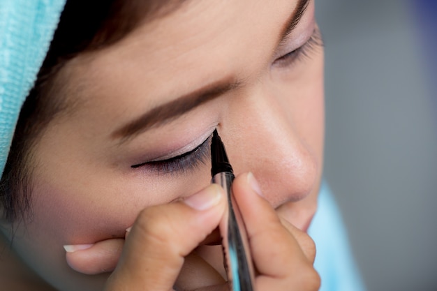 Closeup mujer asiática aplicando delineador de ojos