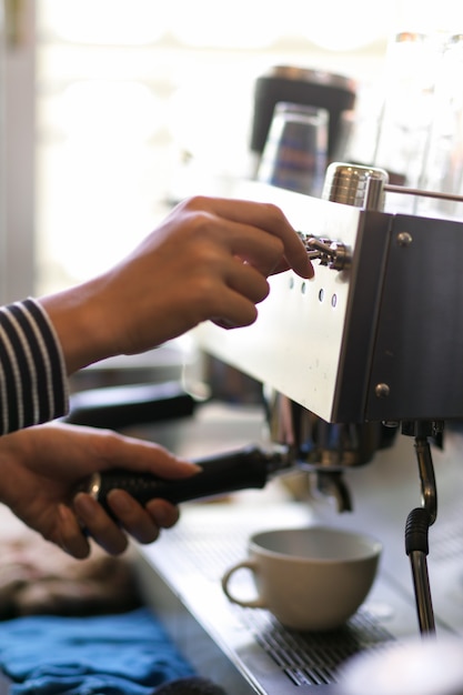 Closeup mujer barista haciendo café preparando pedidos de bebidas con máquina de café en la cafetería.