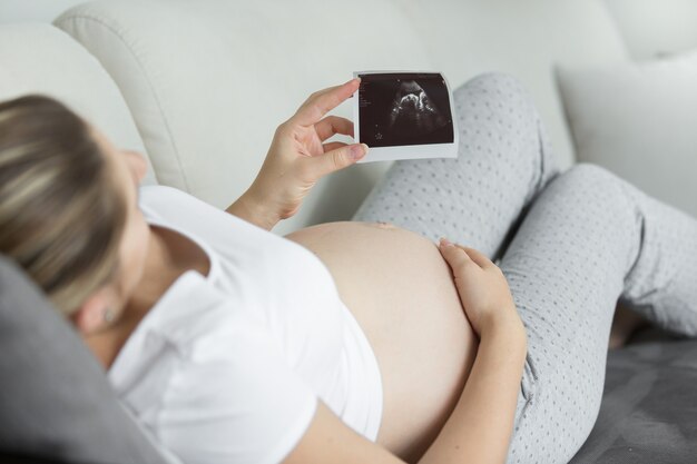 Closeup mujer embarazada mirando imagen de embrión de ultrasonido