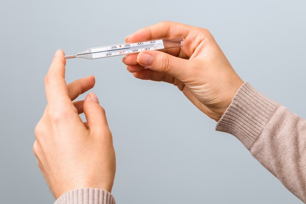 Closeup mujer manos sosteniendo un termómetro de vidrio con alta temperatura por encima de treinta y ocho. síntomas de coronavirus