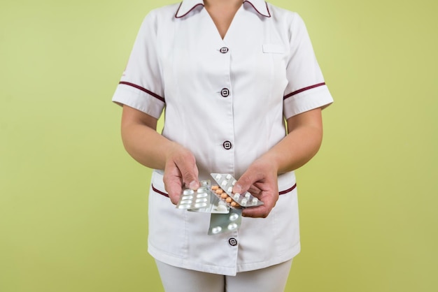 Closeup mujer médico en uniforme blanco con pastillas en sus manos