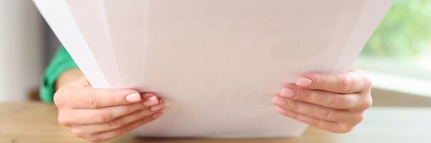 Closeup de una mujer sentada en una mesa y sosteniendo hojas de papel Papel y contabilidad Marketing firma de contratos concepto de acuerdo