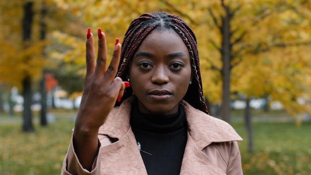 Closeup mulher afro-americana focada séria em pé ao ar livre olhando para a câmera contando de um