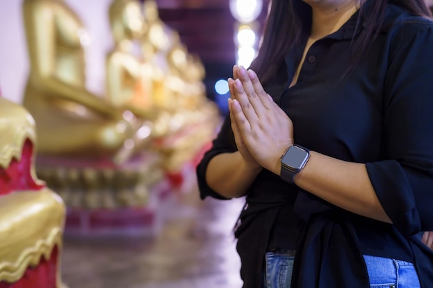 Closeup mulher asiática turista Pague a mão de respeito usando smartwatch com fé na estátua de Buda no templo Tailândia crença no Budismo
