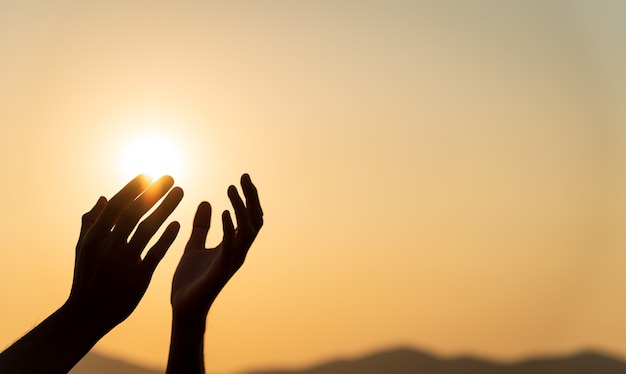 Foto closeup mulher com as mãos orando pela bênção de deus durante o fundo do sol. conceito de esperança e liberdade.