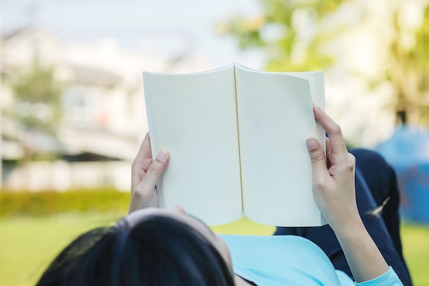 Closeup mulher mentiu no chão de grama para ler um livro no tempo livre no jardim