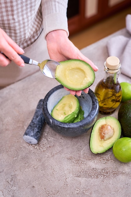 Foto closeup nas mãos segurando abacate fresco cortado ao meio fazendo guacamole