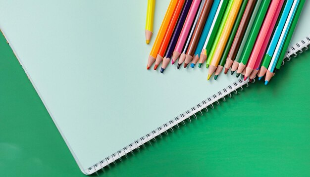 Closeup Notebook e lápis de cor em um plano de fundo verde generativo ai