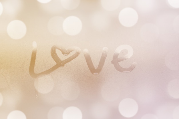 Closeup of love word on glass window with water drop concept design for valentine's day or wedding background