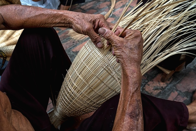 Closeup Old vietnamita hombre artesano manos haciendo la tradicional trampa de peces de bambú o tejer en el