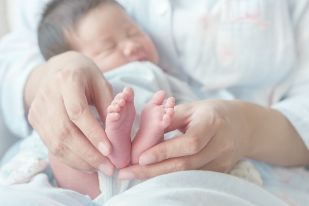 Foto closeup del pie del bebé con la mano de la madre