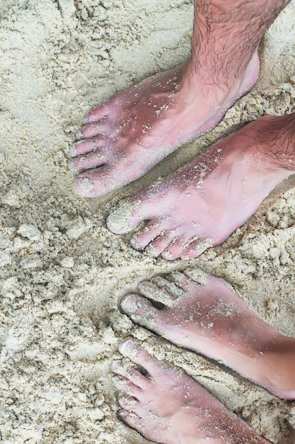 Foto closeup pies de una joven pareja en la playa de arena blanca
