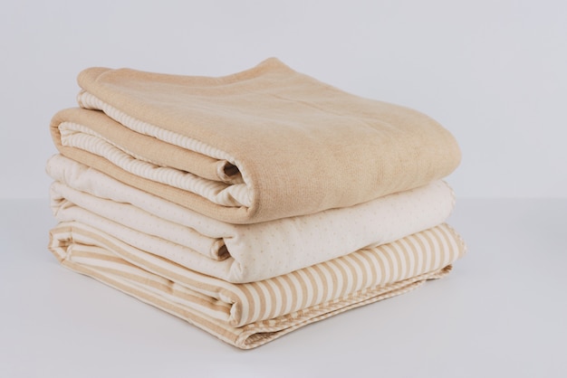 Closeup pilha embrulhado cobertor de algodão bege natural dobrado em branco