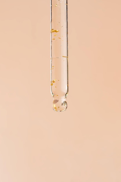 Closeup-Pipette mit einem Hyaluron-feuchtigkeitsspendenden 24-karätigen Goldserum auf beigem Hintergrund Schönheits-Hautpflegekonzept Schönheit und Spa