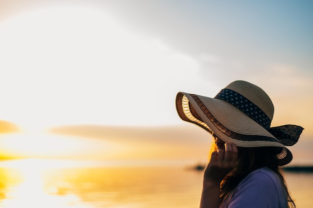 Closeup Portrait einer Frau von hinten in einem Sommerhut bei Sonnenuntergang auf dem Meer auf Reisen