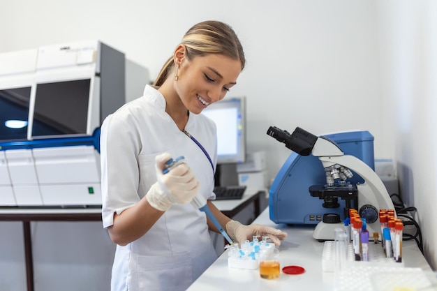 Closeup Portrait Wissenschaftler pipettieren aus 50 ml konischem Röhrchen mit blauer flüssiger Lösung, die Laborexperimente durchführt, isoliertes Labor Forensik Genetik Mikrobiologie Biochemie