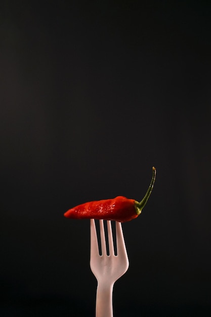 Foto closeup premium-chili in der gabel mit schwarzem hintergrund