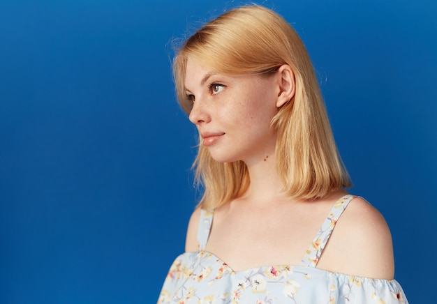 Closeup Profil Porträt eines Mädchens mit Sommersprossen und blonden Haaren gekleidet lässig isoliert blauer Hintergrund