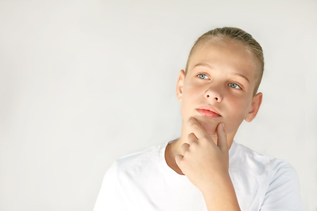 Closeup retrato de un adolescente pensativo con pelo recogido por detrás sobre un fondo blanco.