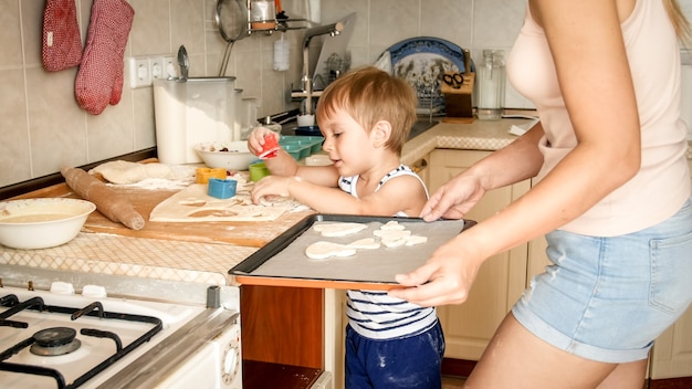 Closeup retrato de adorable niño de 3 años haciendo galletas con la madre